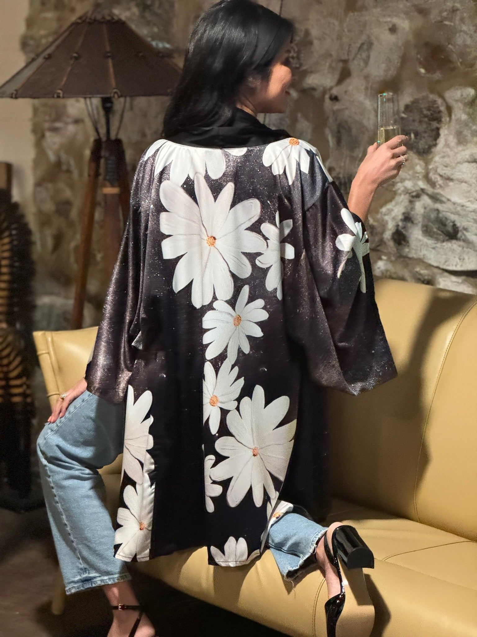 Woman wearing a black kimono with white floral patterns, sitting on a yellow chair.